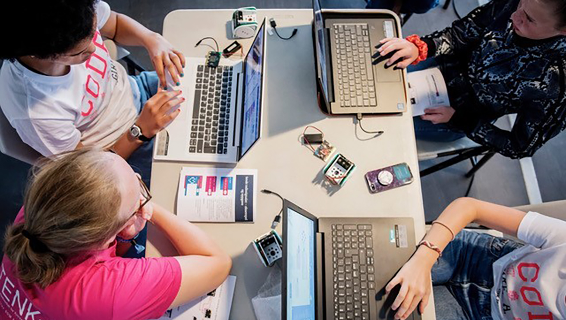 Fire unge jenter sitter og taster på hver sin laptop